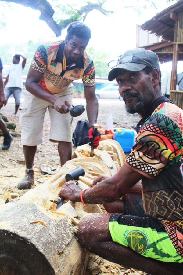Philemon (right) and his father doing the final touches on their carving at the Melanesian Arts and Culture village on Monday.